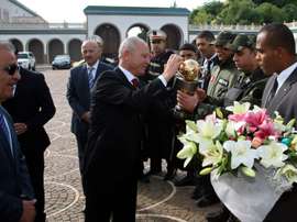 Etoile du Sahels club President Ridha Charfeddine (C) offers flowers before giving the Confederation of African Football trophy to presidential guards on December 2, 2015 at Carthage Palace in Tunis