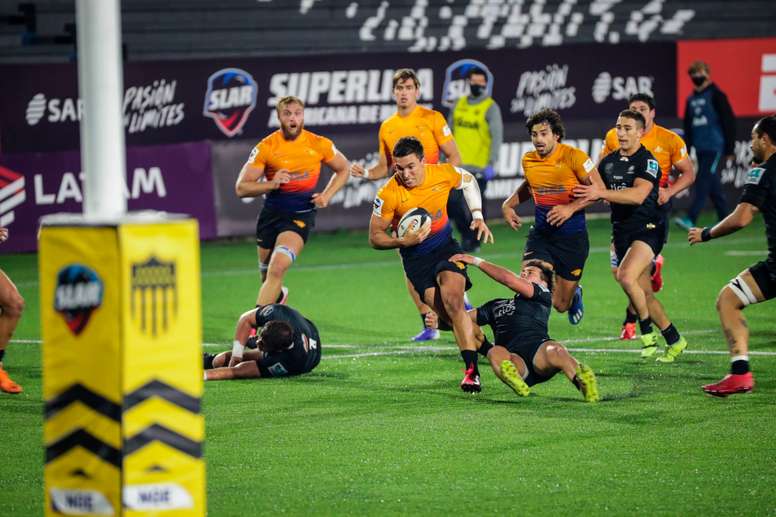 El jugador del Jaguares XV Tomás Cubilla (c) ante la marca de Máximo Ledesma (der) del Olimpia Lions durante la semifinal de la Superliga Americana de Rugby (SLAR), hoy en el estadio Charrúa en Montevideo (Uruguay). EFE/Federico Anfitti