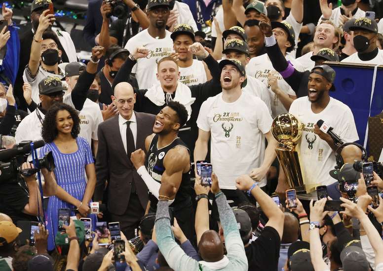 Giannis Antetokounmpo (c) de los Milwaukee Bucks celebra frente al comisionado de la NBA, Adam Silver (i), tras vencer a los Phoenix Suns en las Finales de la NBA en el Fiserv Forum en Milwaukee, Wisconsin (EE.UU.), hoy 20 de julio de 2021. EFE/EPA/TANNEN MAURY