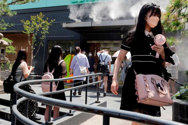 Una mujer sostiene un ventilador para combatir las altas temperaturas en el barrio de Harajuku, en Tokio, Japón, este jueves, en la víspera de la ceremonia de apertura de los Juegos Olímpicos de Tokio 2020. EFE/Kai Försterling